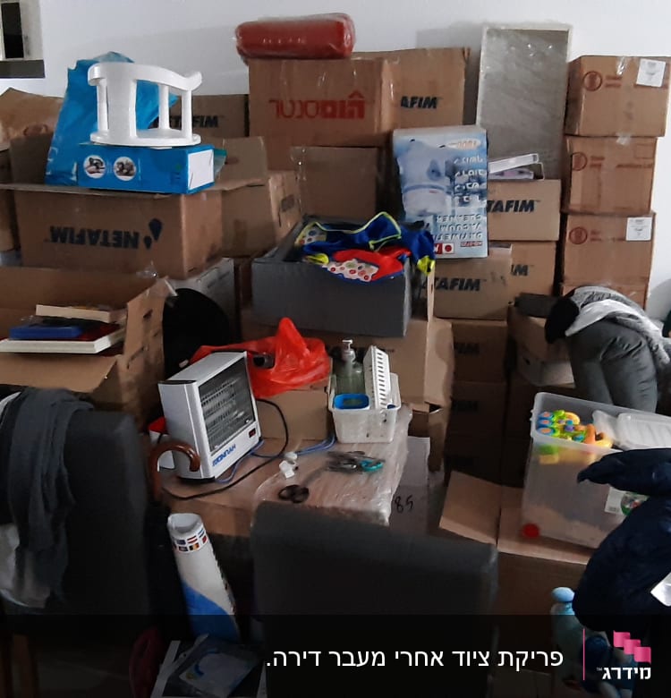 חדר מלא בארגזים, בגדים וכלי בית מפוזרים